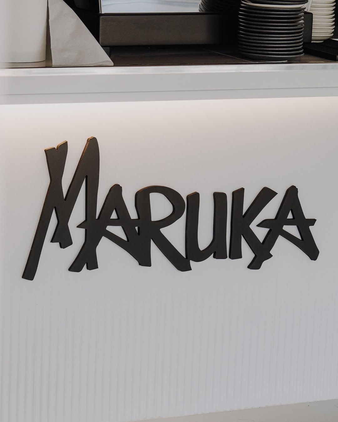 Logotipo Maruka en la pared de la barra, junto a la cafetera