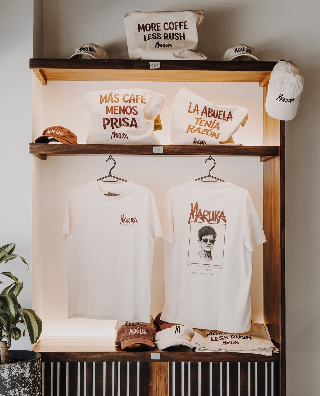 Estantería con camisetas, gorras y bolsas de tela de Maruka
